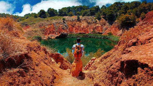 Man standing on rock by lake during autumn