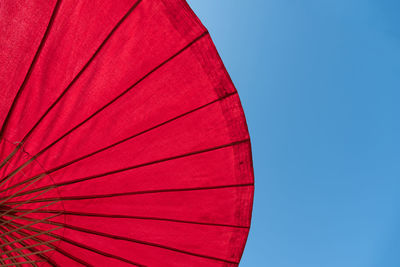 Low angle view of red umbrella against clear blue sky