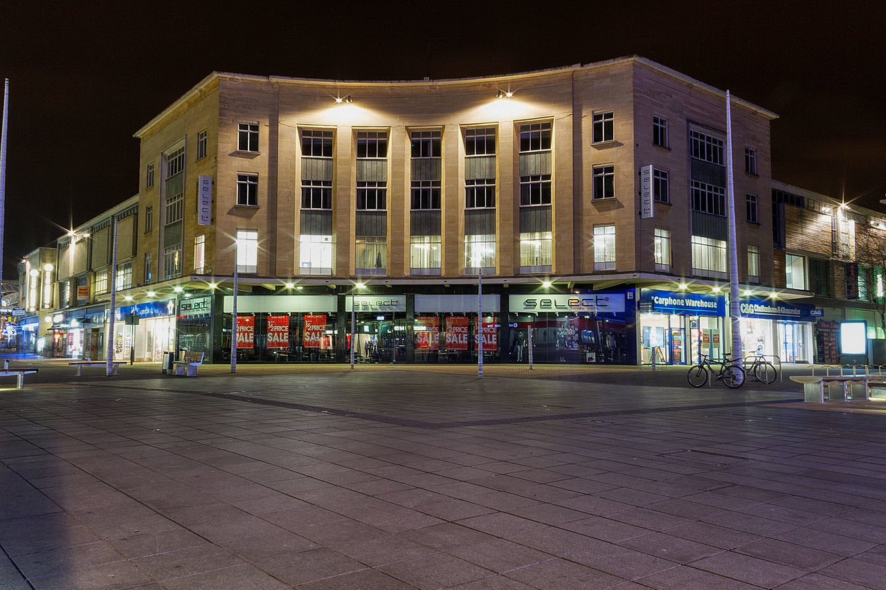 ILLUMINATED STREET BY BUILDINGS AGAINST SKY