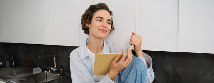 Portrait of young woman standing against wall