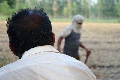 Rear view of mid adult man standing at farm