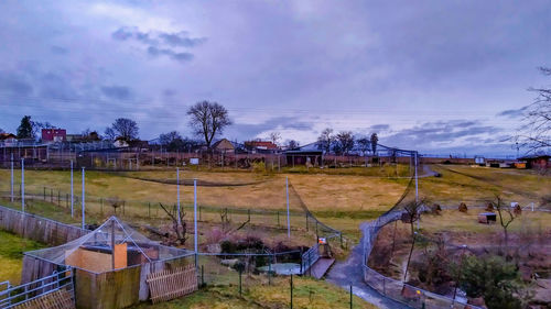 Houses and trees on field against sky