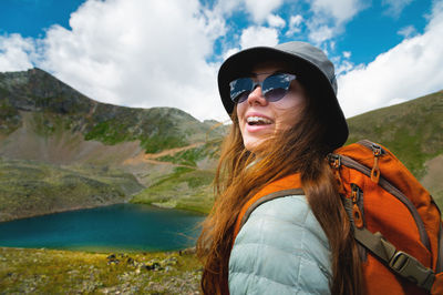 Portrait of a girl in the mountains standing looking at the mountain landscape. happy woman in a cap