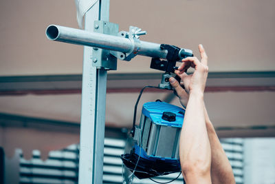 Cropped hands of technician adjusting spotlight at stage theater