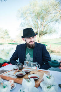 Smiling man looking away while tea ceremony outdoors