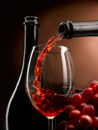 Close-up of wineglass on glass against black background
