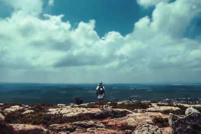 Woman standing on rocks by sea against sky