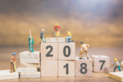 Figurines working over toy blocks with numbers on table