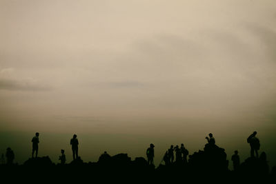 Silhouette people photographing against sky during sunset