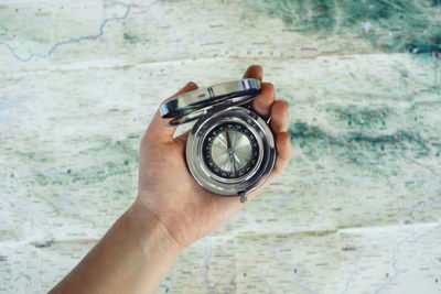 Cropped hand holding navigational compass over map