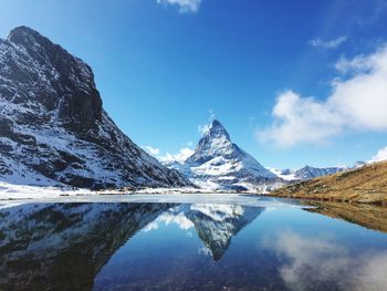 Reflection of mountains and lake against blue sky