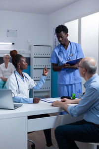 Doctor talking with nurse in front of patient at clinic