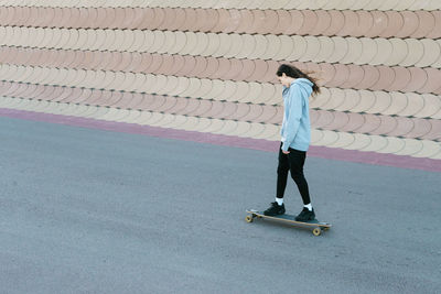 Side view of teenage girl skateboarding on road