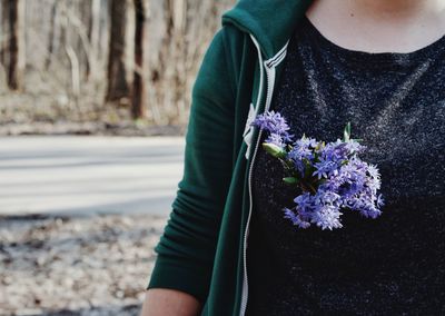 Midsection of woman with purple flowers at roadside
