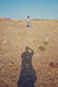 Shadow of man taking photo of a woman from distance 
