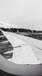 Close-up of airplane wing against sky seen through window