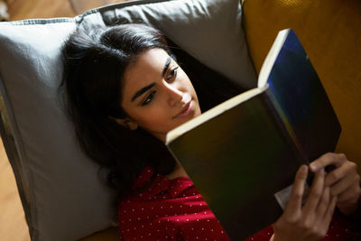High angle view of young woman reading book at home