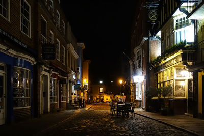 Illuminated street amidst buildings in city at night