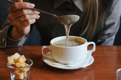 Midsection of woman pouring coffee in cup on table