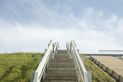 Low angle view of pier on field against sky