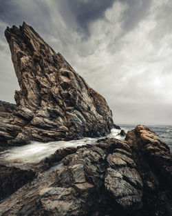 Rock formation on beach against sky