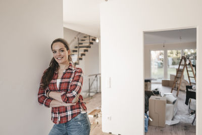 Mature woman standing in her new home, leaning on wall