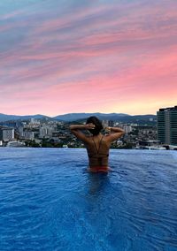 Woman sitting on boat in sea against sky during sunset