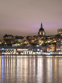 Cityscape view of södermalm stockholm during cloudy night with light reflections in the water.