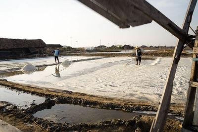 People working at beach against sky