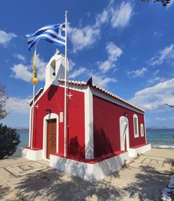 Traditional windmill on beach by building against sky