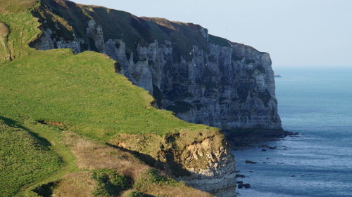 Scenic view of cliff by sea against sky