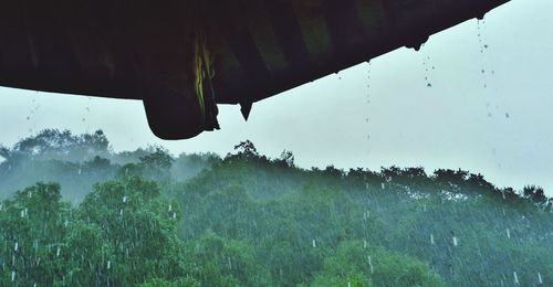 Close-up of raindrops on landscape against sky