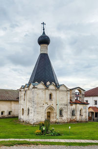 Church on field by building against sky