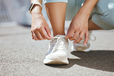 Low section of woman tying shoelace