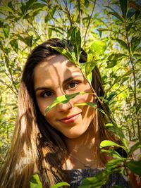 Portrait of smiling young woman against plants