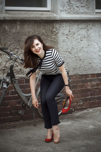 Portrait of young woman standing against wall