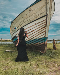 Rear view of woman standing by abandoned boat