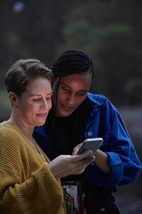 Smiling female couple using smart phone outdoors