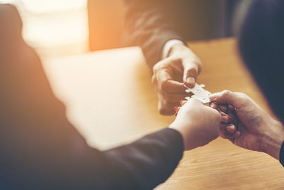 Midsection of business people playing with jigsaw puzzle on table