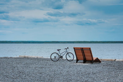 Bicycle by sea against sky. retro styled photo of bicycle near bench on beach.