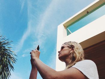 Low angle view of woman using mobile phone against sky