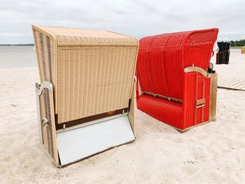 Hooded chairs at beach against sky