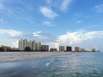 Sea by city against sky