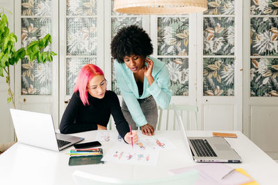 Woman using phone while sitting on table