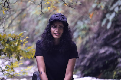 Portrait of smiling young woman standing against trees