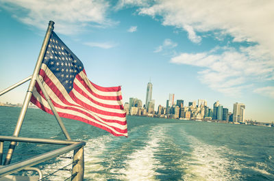 Flag by sea against buildings in city against sky