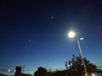 Low angle view of illuminated street light against blue sky