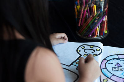 Girl drawing on book at table