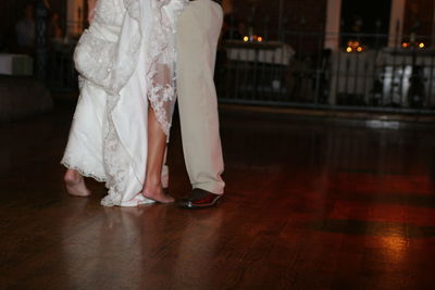 Low section of bride and groom standing on hardwood floor