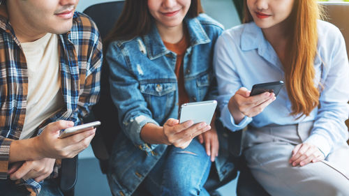 Friends using phone while sitting